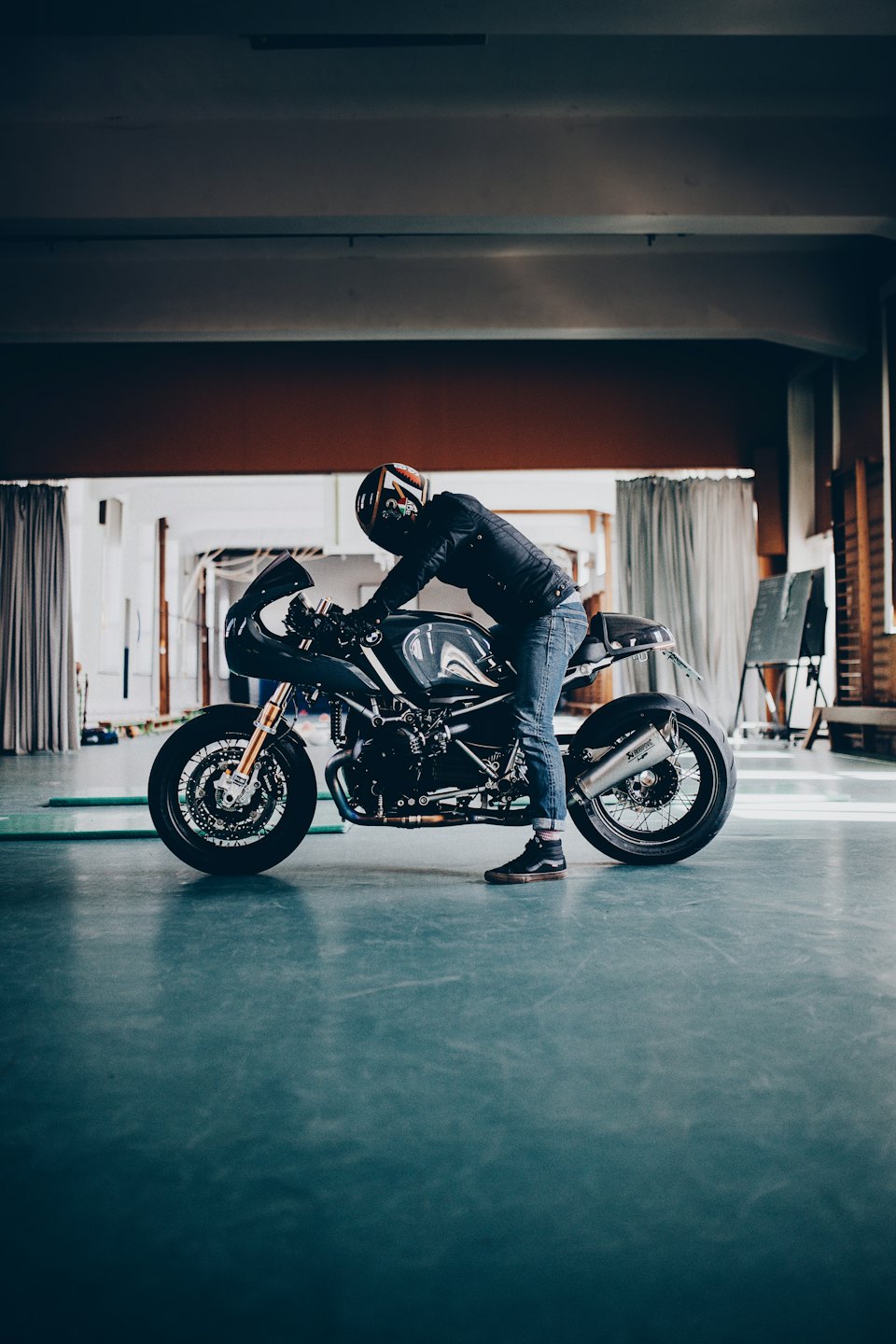 Rider in a leather jacket inspects a custom motorcycle.